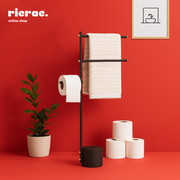 Rolvik- Metal Towels Stand holding towels and toilet paper on a stylish black stand against a red background.