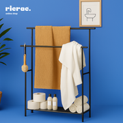 Revos- Metal Rack holding towels and toiletries on a blue background, enhancing bathroom organization and style.