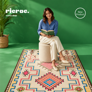Woman reading on a Printed Kilim rug, showcasing earth tones and heritage motifs in a bohemian setting.