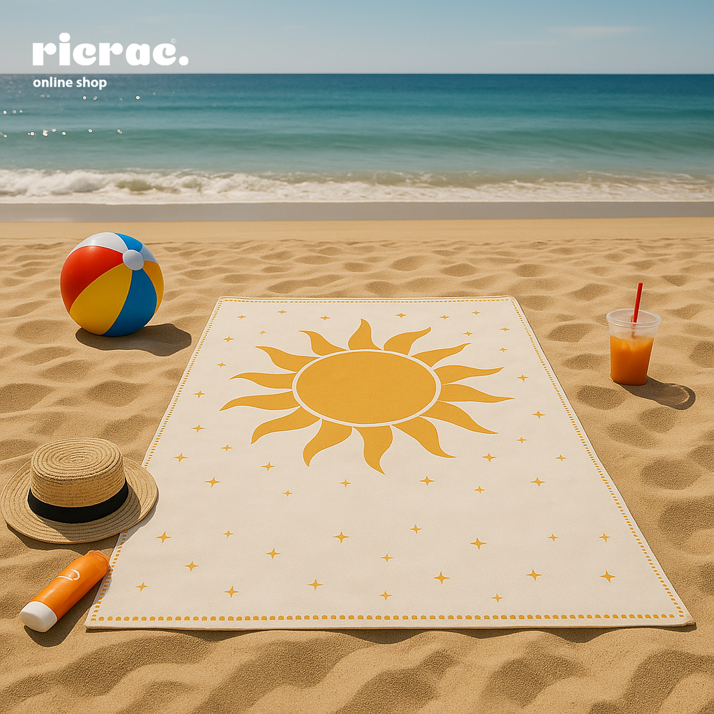Raya -Microfiber Towel on a sandy beach with sun design, beach ball, and refreshing drink for summer relaxation.