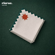 Waterproof cutlery napkins with orange star motifs, featuring a green zigzag border, neatly arranged on a table.