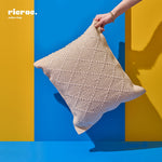 Beige and white criss cross Kilim Cushion held against a vibrant blue and yellow background.