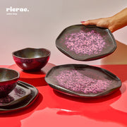 Handmade dinnerware set featuring three unique plates and bowls with a stylish pink and black speckled finish.