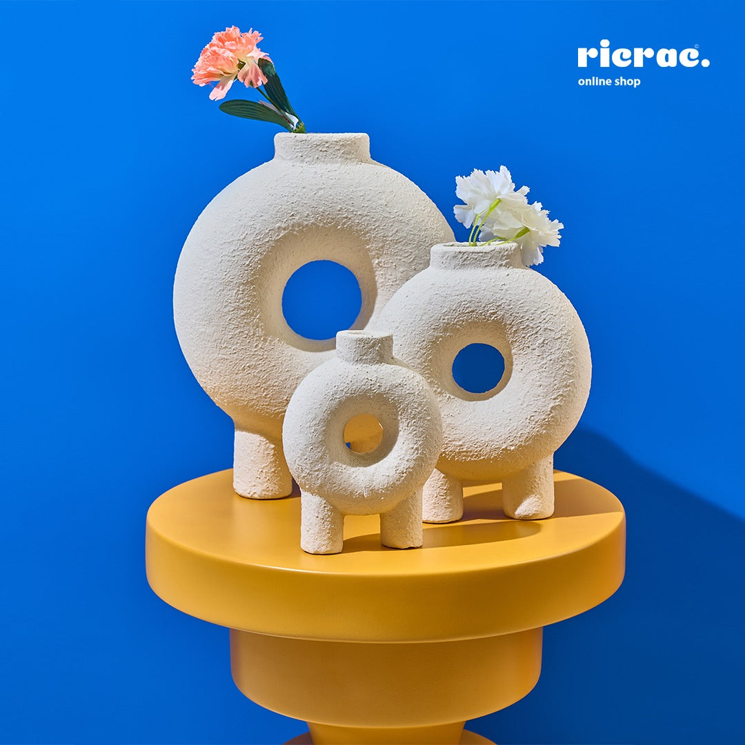 Rounda Accessory Set featuring handcrafted pottery vases with flowers against a bright blue background.