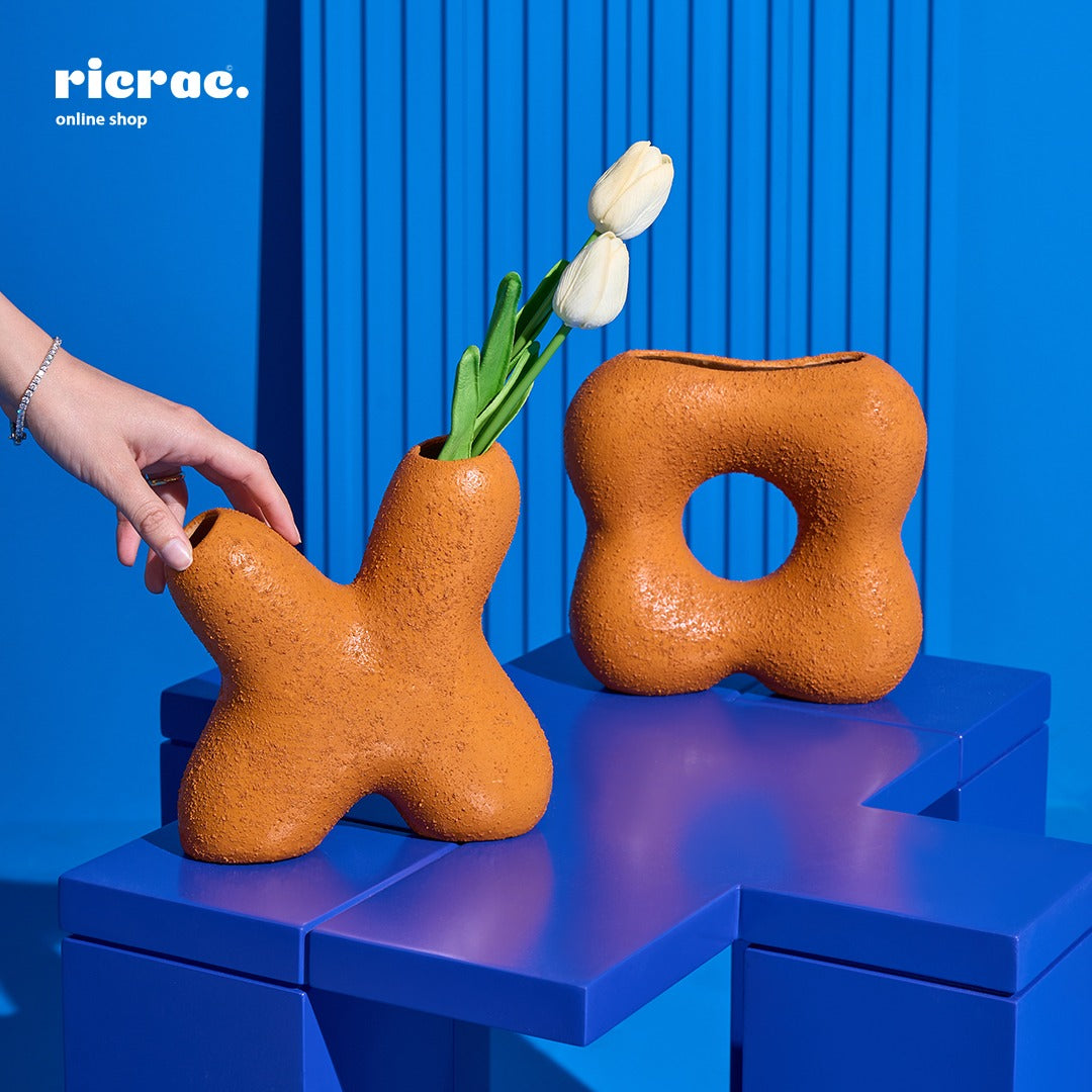 Handcrafted clay accessory showcased in a vibrant blue setting, featuring unique shapes and a flower arrangement.