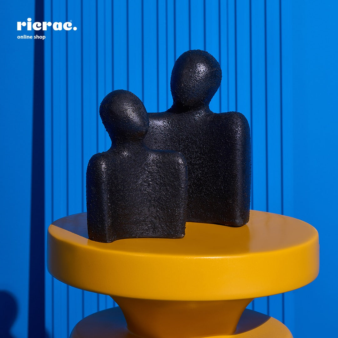 Handcrafted black clay accessory sculpture on a yellow table, enhancing modern decor.