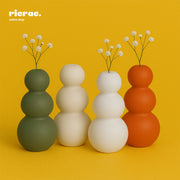 Sculptural Clay Vase in triple form curve design, featuring stacked round shapes in green, white, and orange against a yellow background.