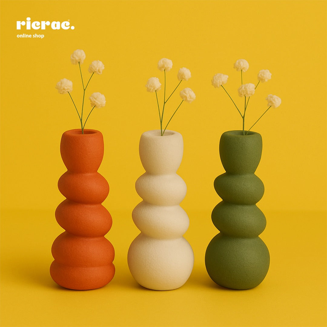 Colorful sculptural clay vases with floral arrangements on a yellow background. Perfect decor for any space.