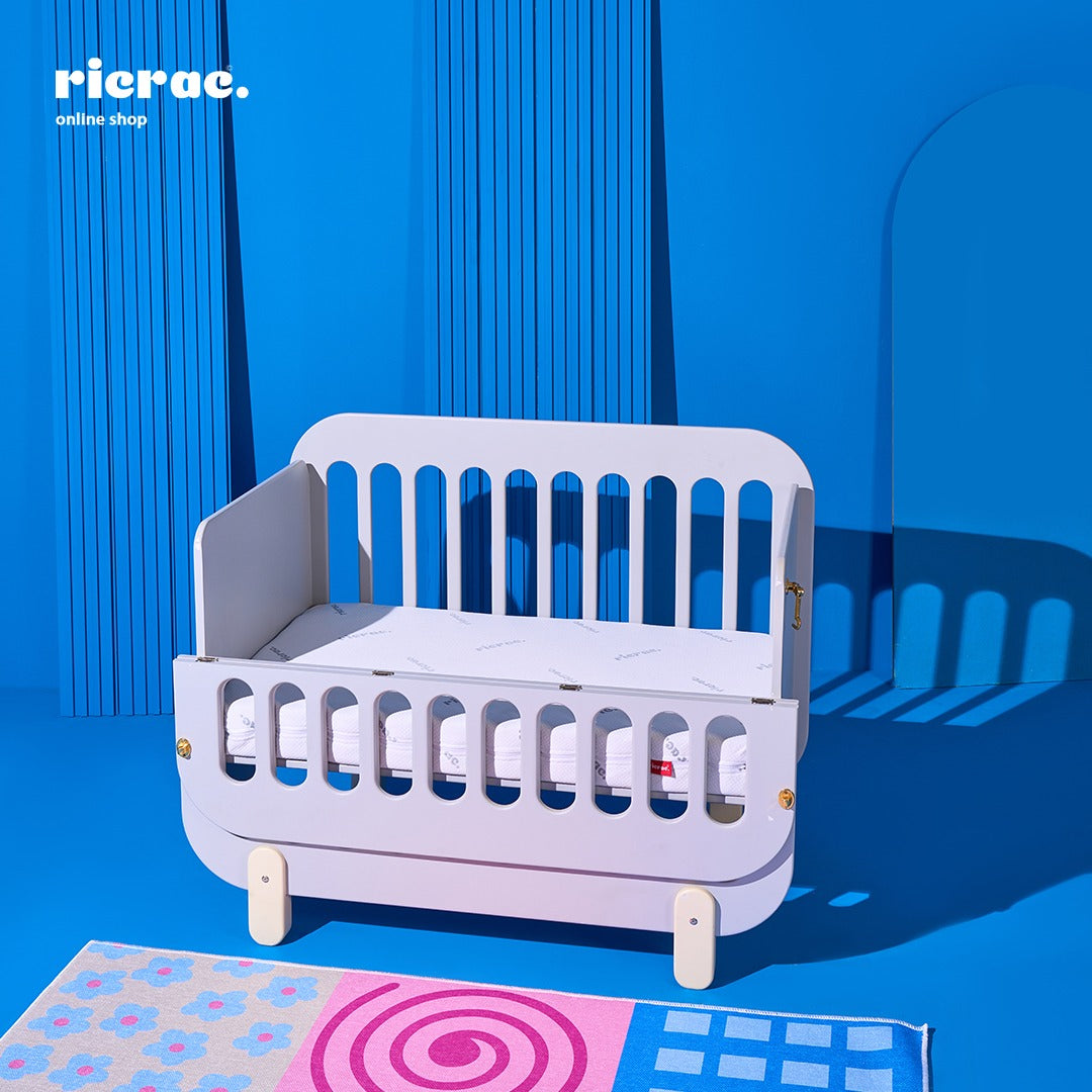 Refook- Baby Cot Bed with a side changing unit on a blue background, featuring an opening side for convenience.