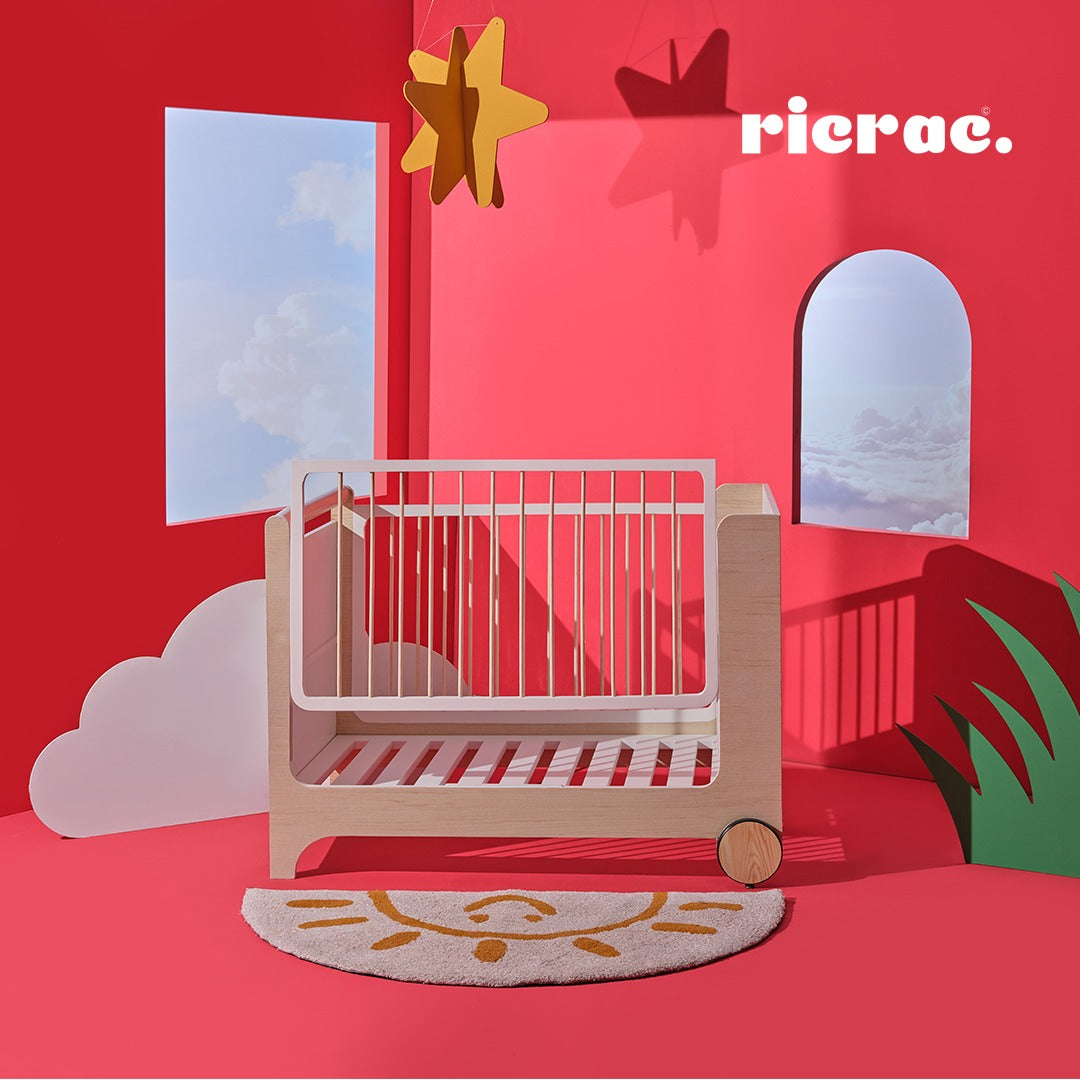 Rolata- Baby Cot Bed displayed in a playful nursery with vibrant red walls and whimsical decor.