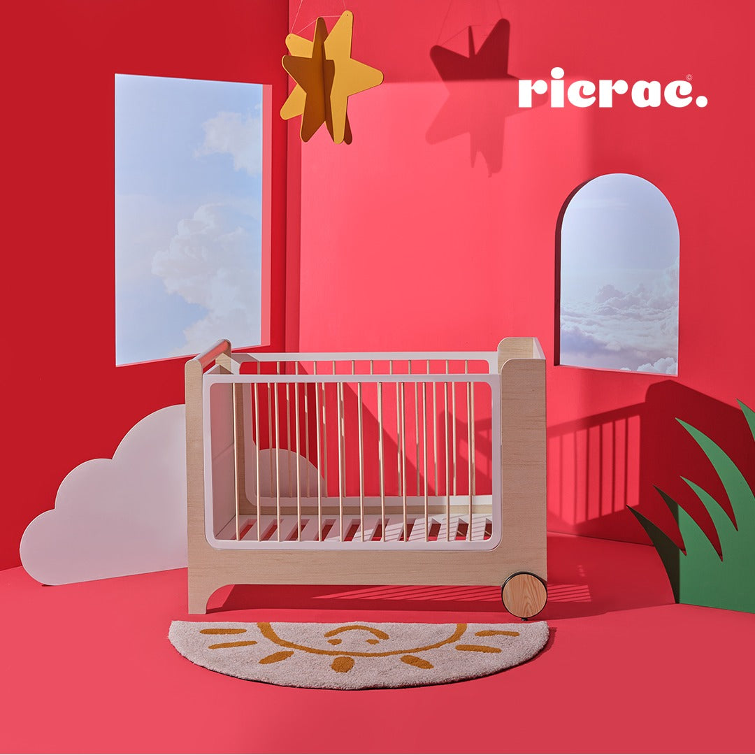 Rolata- Baby Cot Bed displayed in a colorful nursery with stars and clouds in the background.