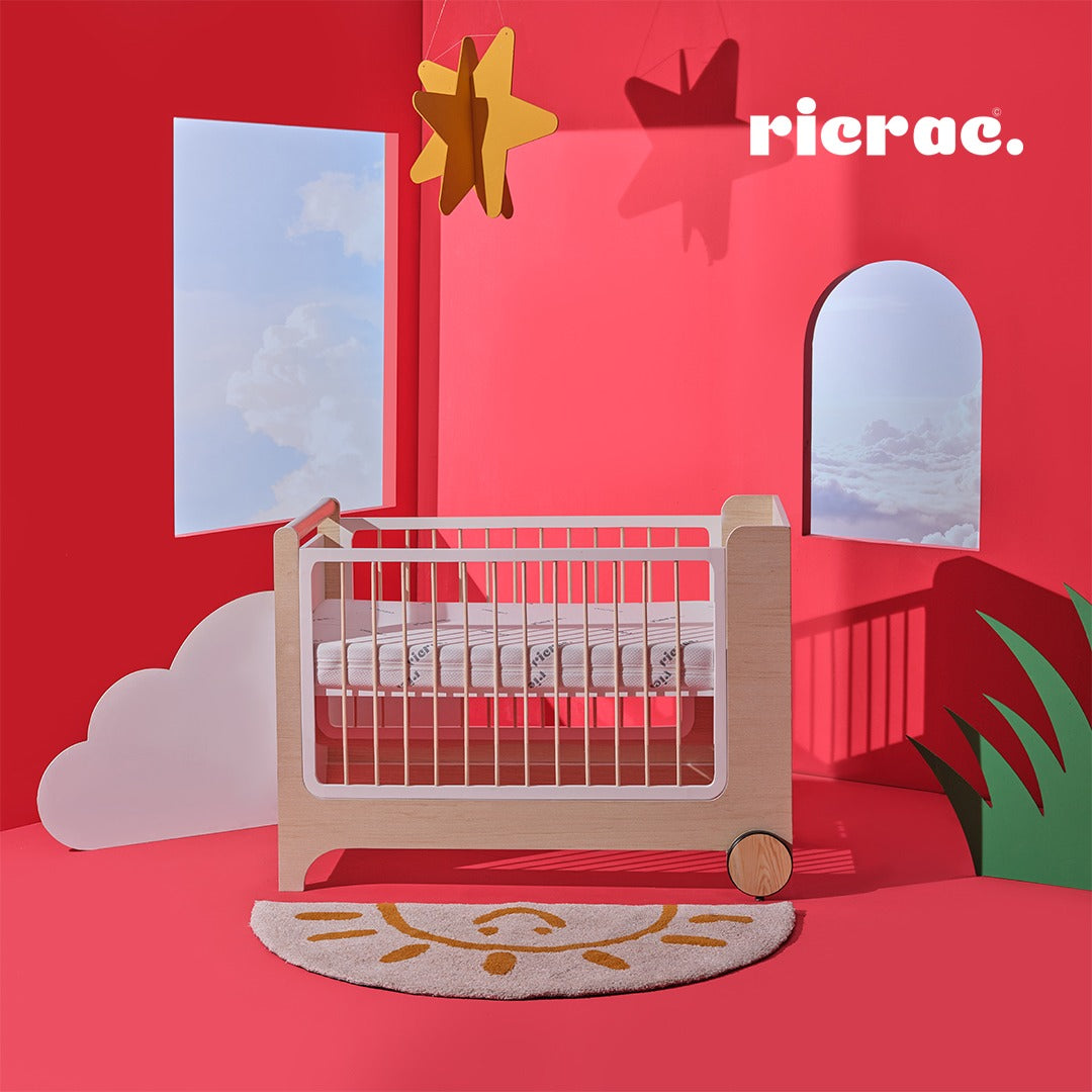 Rolata- Baby Cot Bed in a colorful room with red walls and playful decor, featuring a classic design and elegant details.