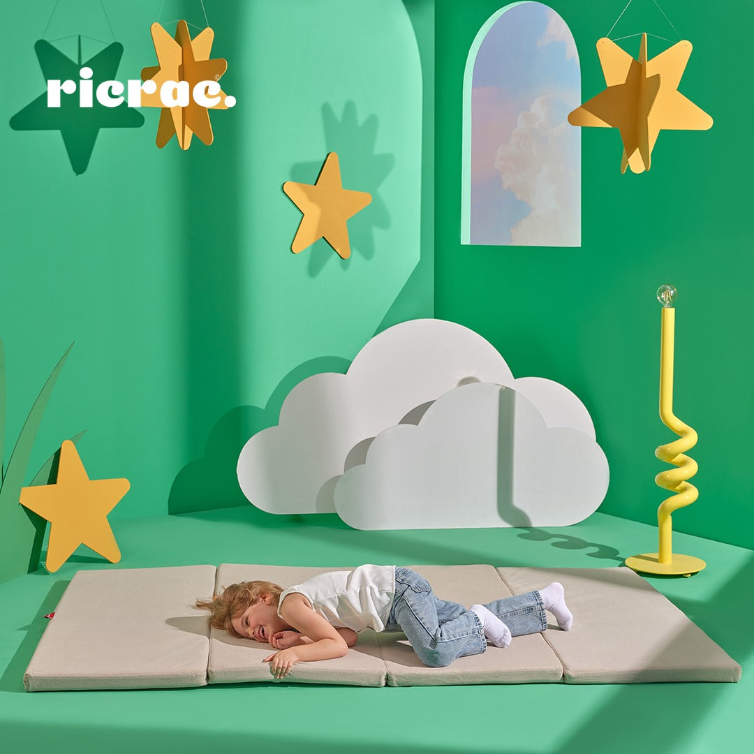 Child resting on Rolata- Kids' Foldable Play Mat in a playful, colorful environment with stars and clouds.