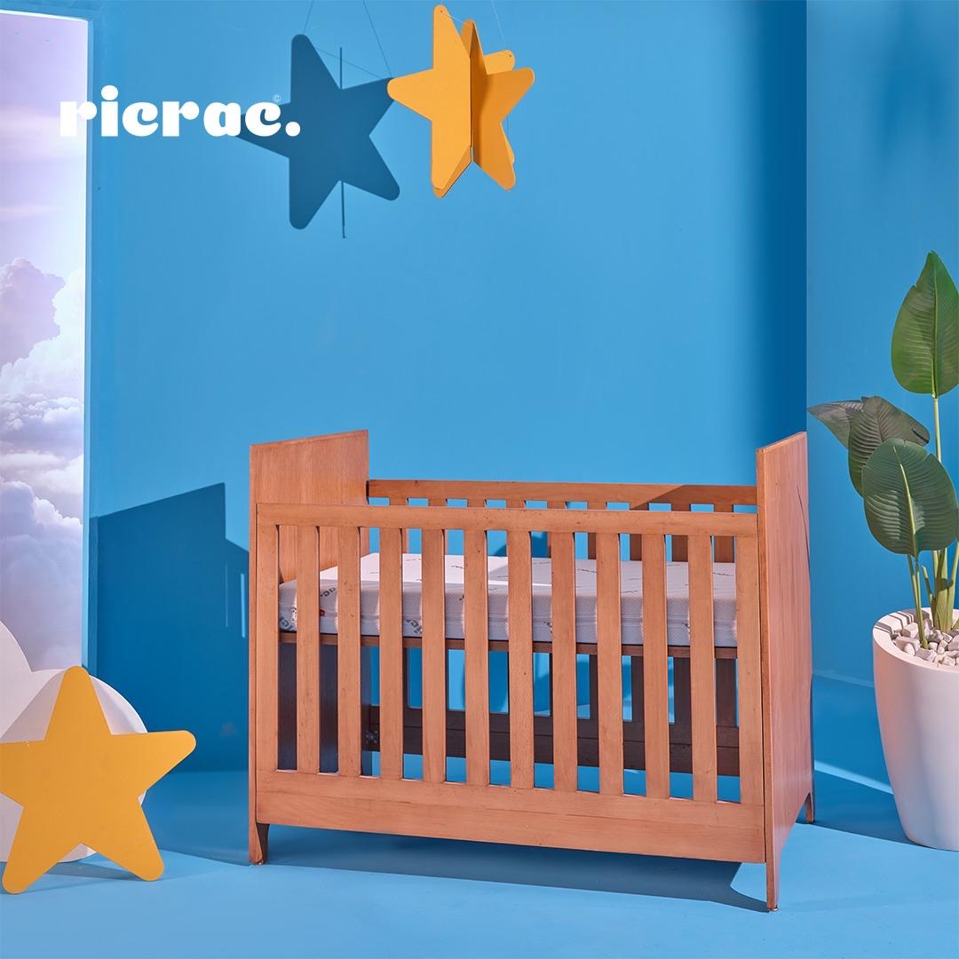 Rafand baby cot bed with a classic design against a colorful backdrop, featuring detailed craftsmanship and adjustable height.